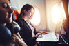 Woman on plane, using laptop, with foam earplug in her ear